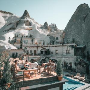 a group of people sitting at a table in front of a mountain at Local Cave House in Göreme