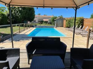 a swimming pool with chairs and an umbrella at Les Cerisiers in Chaunay