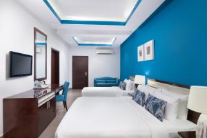 a hotel room with a bed and a blue wall at Al Hail Waves Hotel Managed By Centara in Seeb