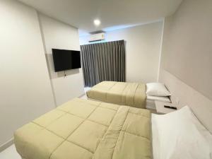 Habitación de hotel con 2 camas y TV de pantalla plana. en Mangkon Hostel en Bangkok