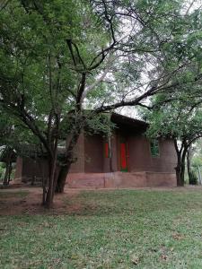 a house with a red door and some trees at Clay Hut Village in Polonnaruwa