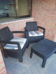 dwa wiklinowe krzesła i stołek siedzący obok ściany z cegły w obiekcie Apartamento El Prado w mieście Almazán
