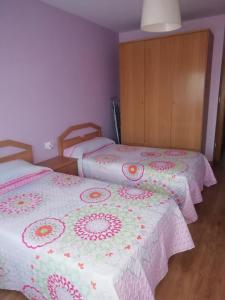 two beds in a room with pink and white blankets at Apartamento El Prado in Almazán