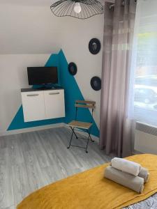 1 dormitorio con 1 cama, TV y silla en la parisienne ( 4 km de rouen ), en Le Mesnil-Esnard