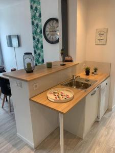 uma cozinha com um lavatório e uma pizza no balcão em la parisienne ( 4 km de rouen ) em Le Mesnil-Esnard