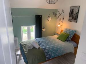 een slaapkamer met een bed met blauwe lakens en groene kussens bij la parisienne ( 4 km de rouen ) in Le Mesnil-Esnard