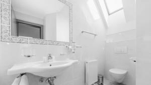 Baño blanco con lavabo y aseo en Hotel24Steps en Ischgl