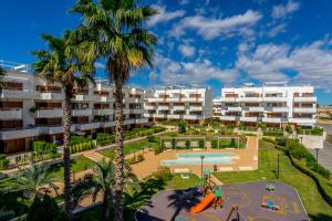 einen Apartmentkomplex mit einem Spielplatz und Palmen in der Unterkunft CB Living - Modern apartment, Terrazas de Campoamor in Orihuela