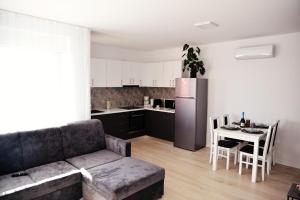 a living room with a couch and a kitchen with a table at Apartament Feeling Home în cartier WestResidence in Oradea