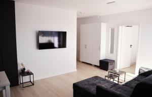 a living room with a couch and a tv on a wall at Apartament Feeling Home în cartier WestResidence in Oradea