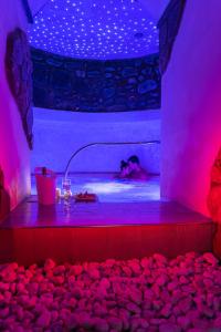 una persona che fa il bagno in una vasca idromassaggio con luci rosa di Hotel & Spa Relais Freedom Club a Massa Lubrense