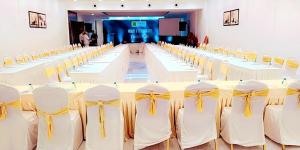 a large conference room with white tables and yellow chairs at coral beach resort in Mahabalipuram