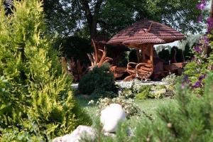 einen Garten mit einem Stuhl und einem Sonnenschirm in der Unterkunft Hotel Zameczek in Książ Wielki