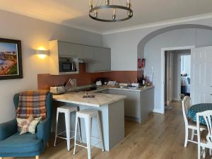 a kitchen and living room with a island and chairs at Newton Croft Tenby overlooking North Beach in Tenby