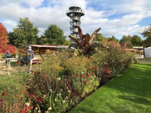 a man standing in front of a garden with a lighthouse at Ferienwohnung Thedo in Bad Zwischenahn