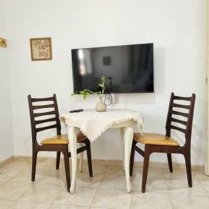 mesa blanca con 2 sillas y TV en la pared en בית פרומן, en Moledet