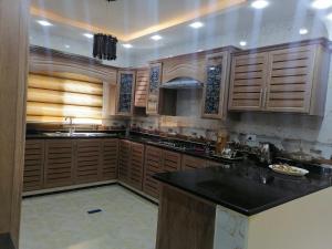 cocina con armarios de madera y encimera negra en Petra Guests home, en Wadi Musa
