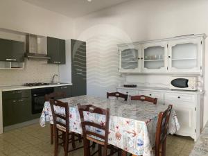 a kitchen with a table and chairs and a kitchen with green cabinets at Villa Tortuga By Cala Salento in Torre Lapillo