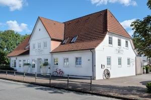 ein weißes Gebäude mit braunem Dach in der Unterkunft Eichhorns in Niebüll
