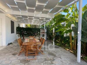 a patio with a table and chairs under a pergola at Villa Tortuga By Cala Salento in Torre Lapillo