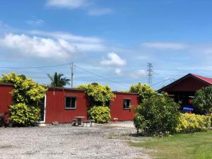 a couple of red buildings with a bench in front at AsiaCamp - Cabin Sungai Sireh in Tanjung Karang