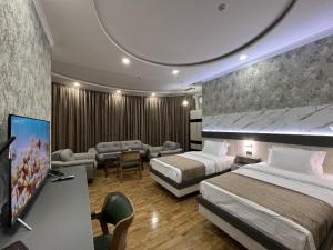 a hotel room with two beds and a flat screen tv at Ada Hotel in Tashkent