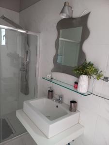 a white bathroom with a sink and a mirror at Mulberry House in Elafonisos