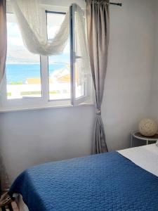- une chambre avec un lit bleu et une fenêtre dans l'établissement Apartmani Nika, à Slatine