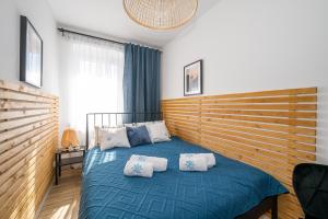 a bedroom with a blue bed with pillows on it at Apartamenty Kapitańskie in Darłówko