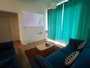 クチンにあるMuji homestay kuching scenic view 2 bedrooms entire apartmentのリビングルーム(青いソファ、テーブル付)