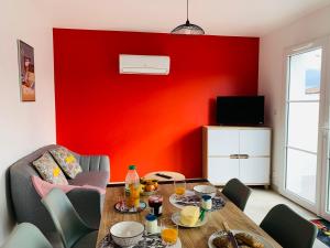 a living room with a table and a red wall at LE MOUSSE Maison avec piscine/parking/wifi/plages 5kms in Les Mathes