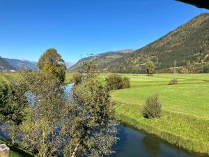 a river in a field with mountains in the background at Appartement Imbachhorn in Zell am See