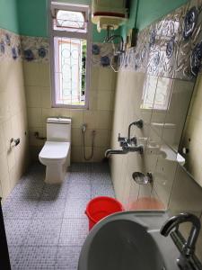 a bathroom with a toilet and a sink and a window at Hotel PineWood Tawang in Tawang