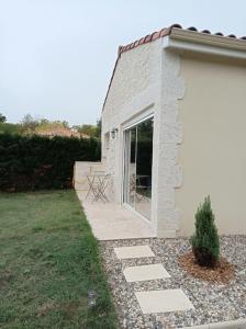 een wit gebouw met een raam en een patio bij Charmant gîte indépendant au calme tout confort in Barbaste