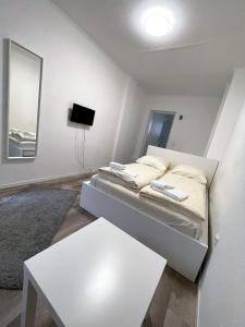 a white bedroom with a bed and a white table at Tyros Hotel und Gästehaus am Weidendamm in Hannover