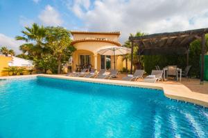a swimming pool with chairs and a house at Villa La Martina - PlusHolidays in Calpe