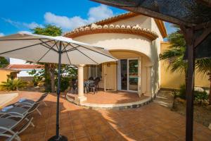 un patio con sombrilla frente a una casa en Villa La Martina - PlusHolidays, en Calpe