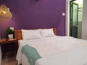 um quarto com uma cama branca e uma parede roxa em Abalone House Quy Nhơn em Quy Nhon