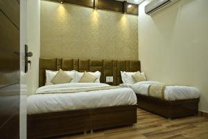 a bedroom with two beds with white sheets and pillows at GUNTAS RESIDENCY in Amritsar