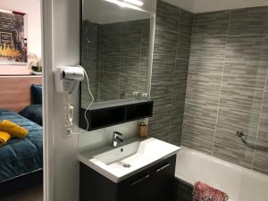 ein Badezimmer mit einem Waschbecken, einem Spiegel und einer Badewanne in der Unterkunft Sandy Eden Superieur in Drancy