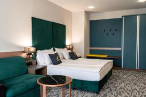une chambre d'hôtel avec un lit et un canapé vert dans l'établissement Santé SPA Hotel, à Velingrad