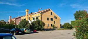 a yellow building with cars parked in a parking lot at Adria Beach Apartment in Cavallino-Treporti