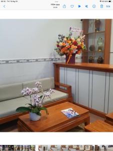 a living room with a couch and a table with flowers at Abalone House Quy Nhơn in Quy Nhon
