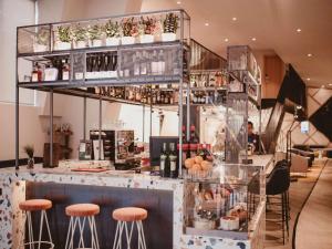 a restaurant with a bar with stools and bottles of wine at Hotel Novotel Sevilla in Seville