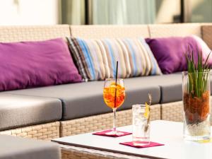 a table with two glasses and a couch at Novotel Basel City in Basel