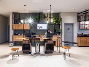 a woman sitting at a desk in an office with a laptop at ibis Botucatu in Botucatu