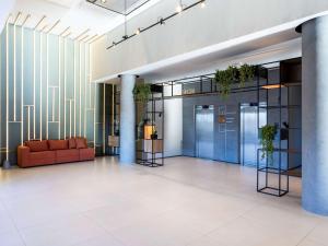 an office lobby with a red couch and plants at ibis Botucatu in Botucatu