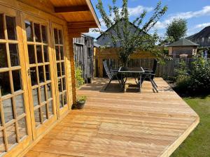 una terraza de madera con mesa y sillas. en Hillview, en Ballater