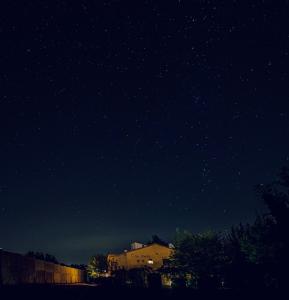 una estrella llena de cielo nocturno con un edificio y árboles en Hostal Can Maret en Fallinas