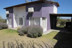 una casa morada y blanca con una puerta y algunos arbustos en Palotes Sierras Apart en Villa Giardino